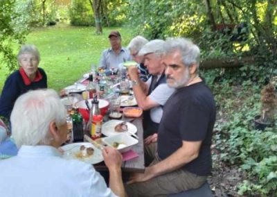 Mitglieder des Schachclubs Büsum sitzen an einem großen Tisch im Garten und essen gemeinsam.